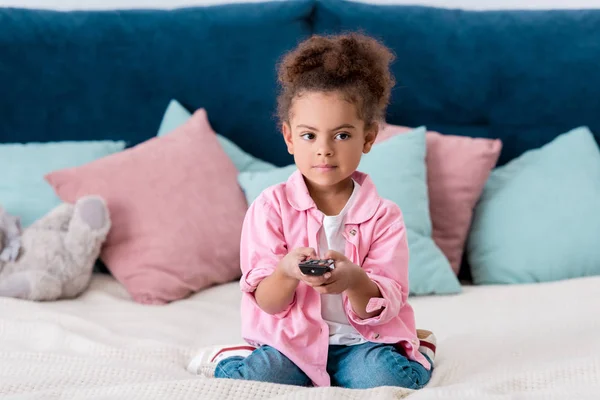 Süße Afrikanisch Amerikanische Kind Sitzt Auf Dem Bett Und Schaltet — Stockfoto