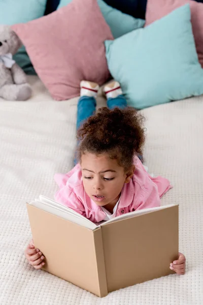 Surprised African American Kid Laying Bed Reading Book — Stock Photo, Image