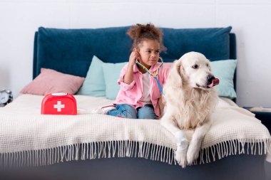 Afro-Amerikan çocuk stetoskop ve köpeği ile oynarken şekillenmeye
