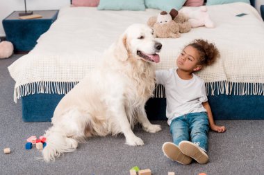 Sevimli küçük Afro-Amerikan çocuk mutlu köpek ile katta oturan