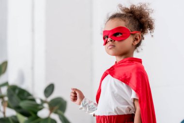 Portrait of cute little african american child in  red superhero costume and mask clipart