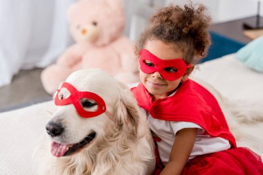 Sevimli küçük Afro-Amerikan çocuk kırmızı süper kahraman maske mutlu köpek ile gülümseyen