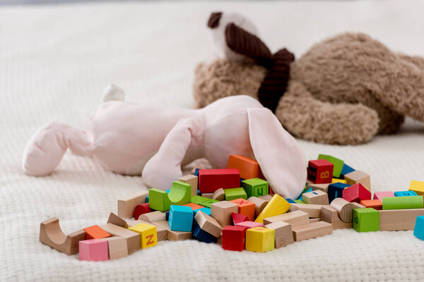 Colourful toy cubes and teddy bears lying on plaid
