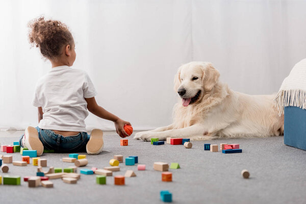 little kid in white t-shirts with happy dog playing with toy cubes