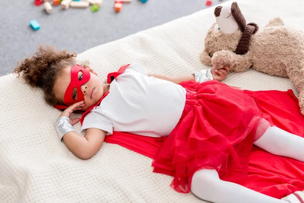 Adorable Niño Afroamericano Traje Superhéroe Acostado Cama Con Oso Peluche — Foto de stock gratis