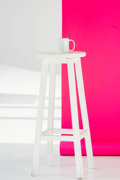白い背景でカップとピンクの壁紙と木製の椅子  — 無料ストックフォト