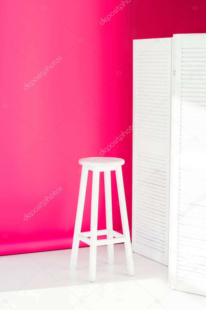 white painted room divider and chair with bright pink wallpaper at background