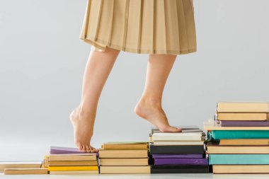close up barefoot woman walking on aged books clipart