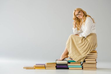 kitapların yapılan basamaklarında oturan gözlüklü mutlu yalınayak kadın  