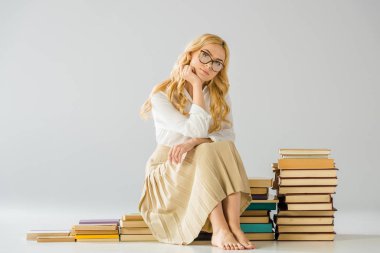 kitapların yapılan basamaklarında oturan gözlüklü çekici düşünceli yalınayak kadın  