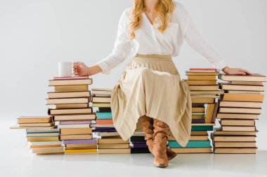 Yetişkin kadının yığın kitap Kupası ile oturan yakın çekim