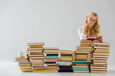 beautiful woman in glasses reading near pile of books clipart