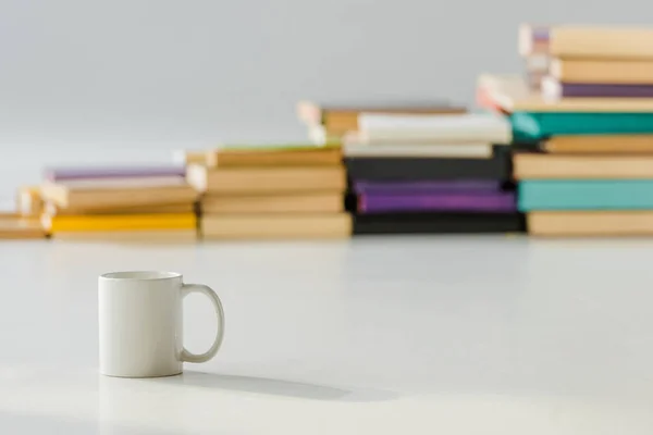 Close Van Een Witte Kop Met Leeftijd Stapel Boeken Achtergrond — Stockfoto