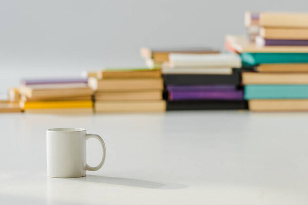 close up of white cup with aged pile of books on background