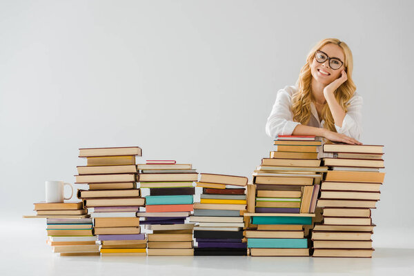 beautiful woman in glasses dreaming near pile of books