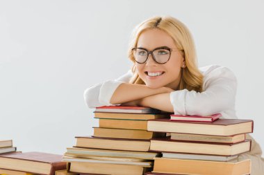 smiling blonde adult woman in glasses with books isolated on grey clipart