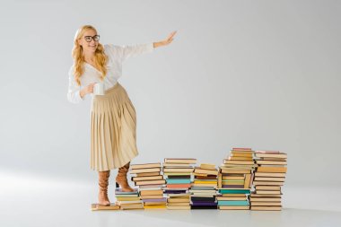 Beyaz kupa ile kitaplar üzerinde duran yetişkin şık kadın 