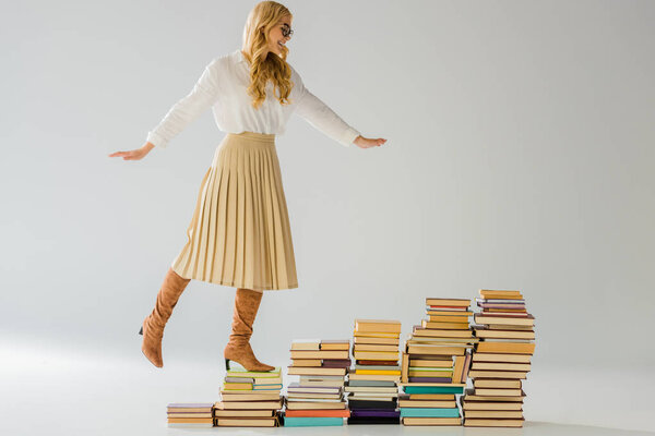 взрослая элегантная женщина балансирует на винтажных книгах
 