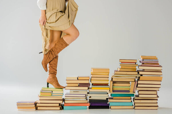 close up of woman in boots walking on vintage books 