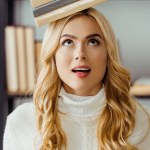 Close up van grappige vrouw met boeken op hoofd