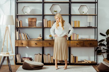 attractive blonde woman standing in loft living room clipart