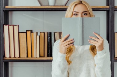 sarışın kadının yüz kitap arkasında saklanıyor yakın çekim