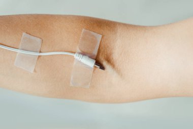 close up of female hand with attached white cable  like medical IV infusion isolated on grey, music concept  clipart