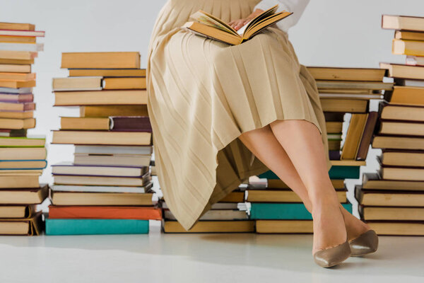 close up of woman reading and sitting on pile of books 