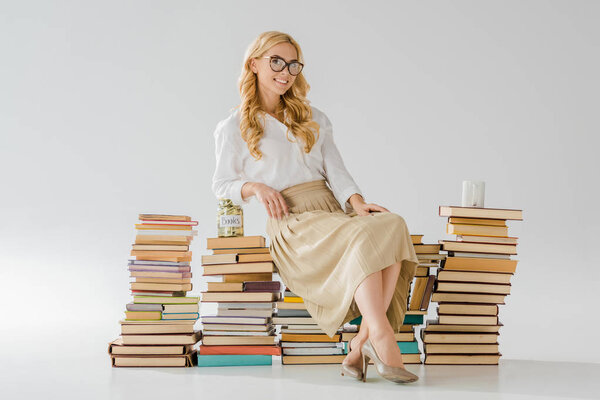 beautiful woman in glasses sitting on books with savings in jar and cup