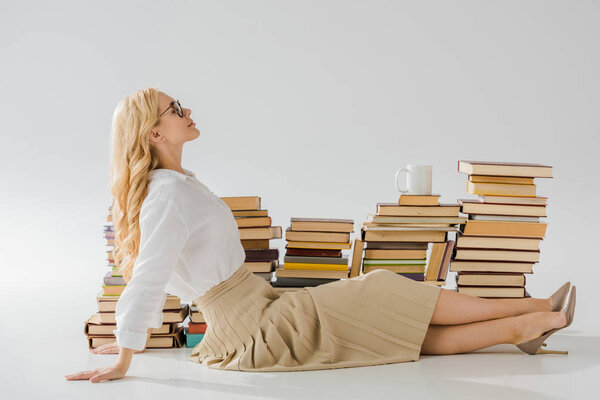 beautiful woman sitting on floor near pile of books 