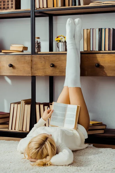 Frau Liegt Auf Teppich Und Liest Buch Mit Beinen Auf — Stockfoto