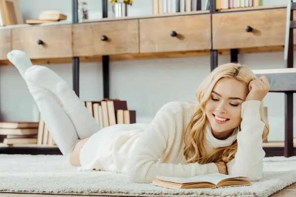 Uśmiechnięta Kobieta Leżąc Dywanie Czytanie Książki — Zdjęcie stockowe