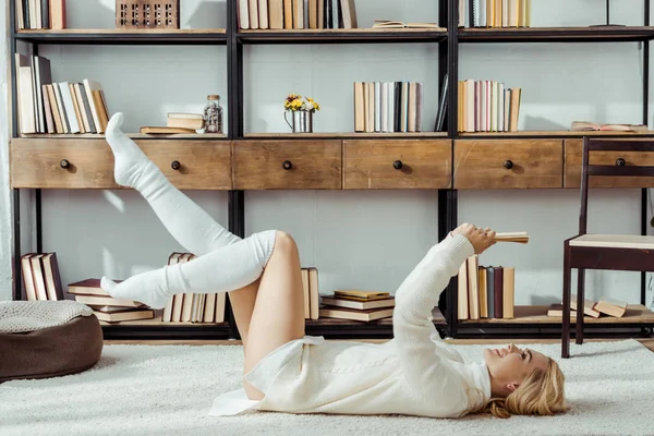 Lächelnde Frau Legt Sich Auf Teppich Und Liest Buch — Stockfoto