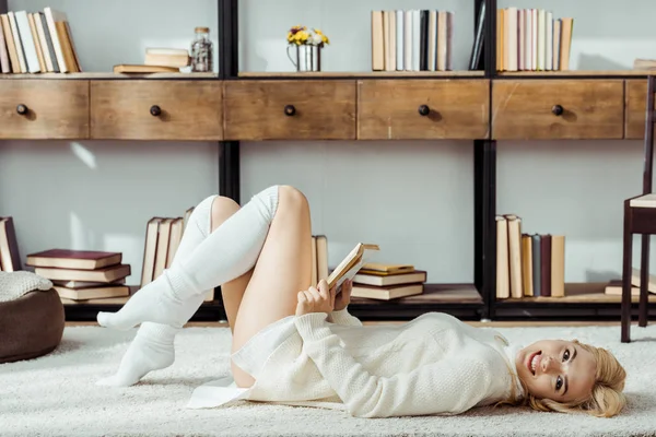 Lächelnde Schöne Frau Die Auf Teppich Liegt Und Buch Liest — Stockfoto