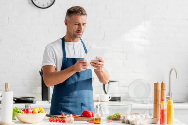 man with digital tablet in hands standing at kitchen clipart