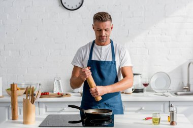 adult handsome man salting steak with salt mill clipart