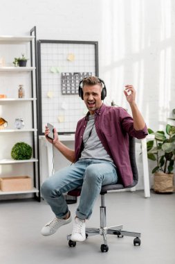 müzik dinleme ve yüksek sesle şarkı office evde sandalyede otururken adam