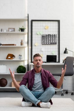 man sitting on floor and practicing yoga at home office
