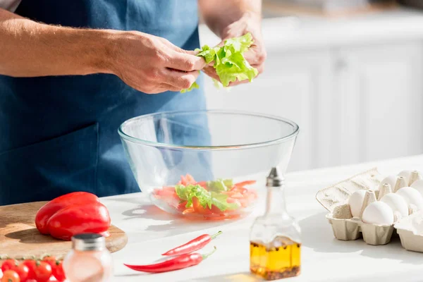 レタスのサラダを作る手を持つ男の部分的なビュー — ストック写真