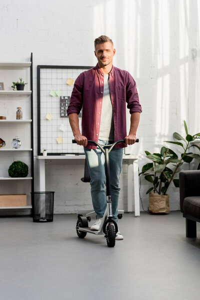 smiling man riding scooter at home office