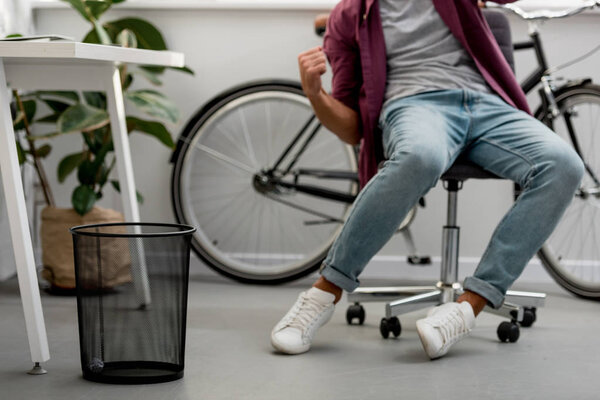 обрезанный вид человека, бросающего мусор в корзину
