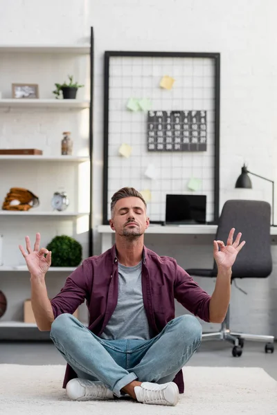 男人坐在地板上 在家里的办公室练习瑜伽 — 图库照片