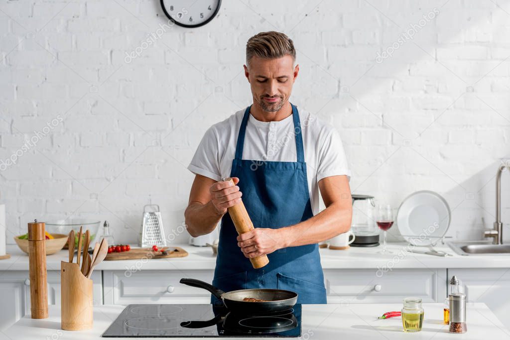 adult handsome man salting steak with salt mill