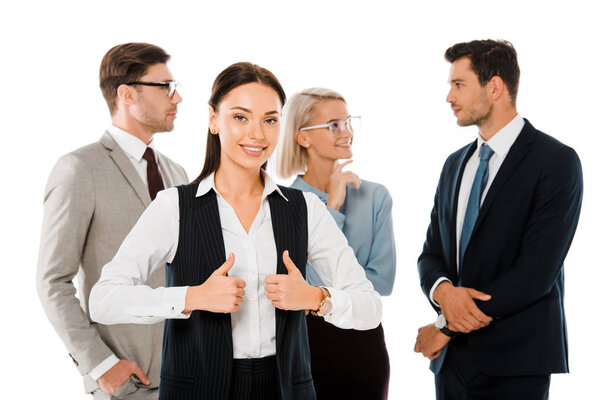 successful businesswoman showing thumbs up and standing with colleagues isolated on white