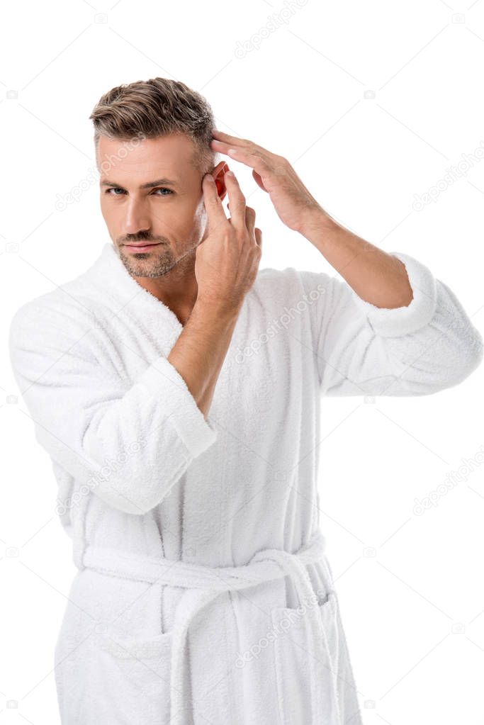 adult man in bathrobe checking himself for hair loss isolated on white