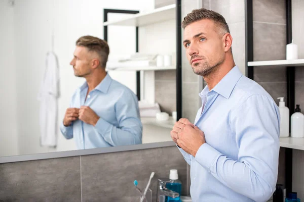 Pensive Adult Businessman Buttoning Blue Shirt Bathroom Home — Stock Photo, Image