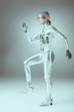side view of futuristic cyborg walking on grey, future technology concept    clipart
