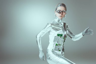 Gümüş cyborg yürüyüş ve kameraya gri, geleceğin teknoloji kavramı üzerinde seyir 