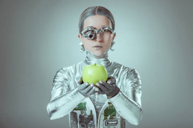 robot Apple holding ve izole gri, geleceğin teknoloji kavramı üzerinde kamera bakıyor  