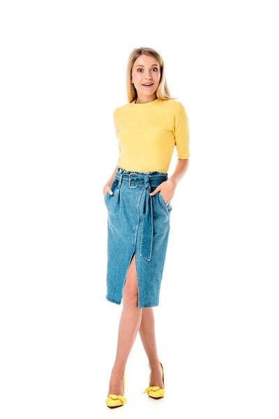 Вид в полный рост красивой удивленной девушки, смотрящей на камеру изолированную на белом
